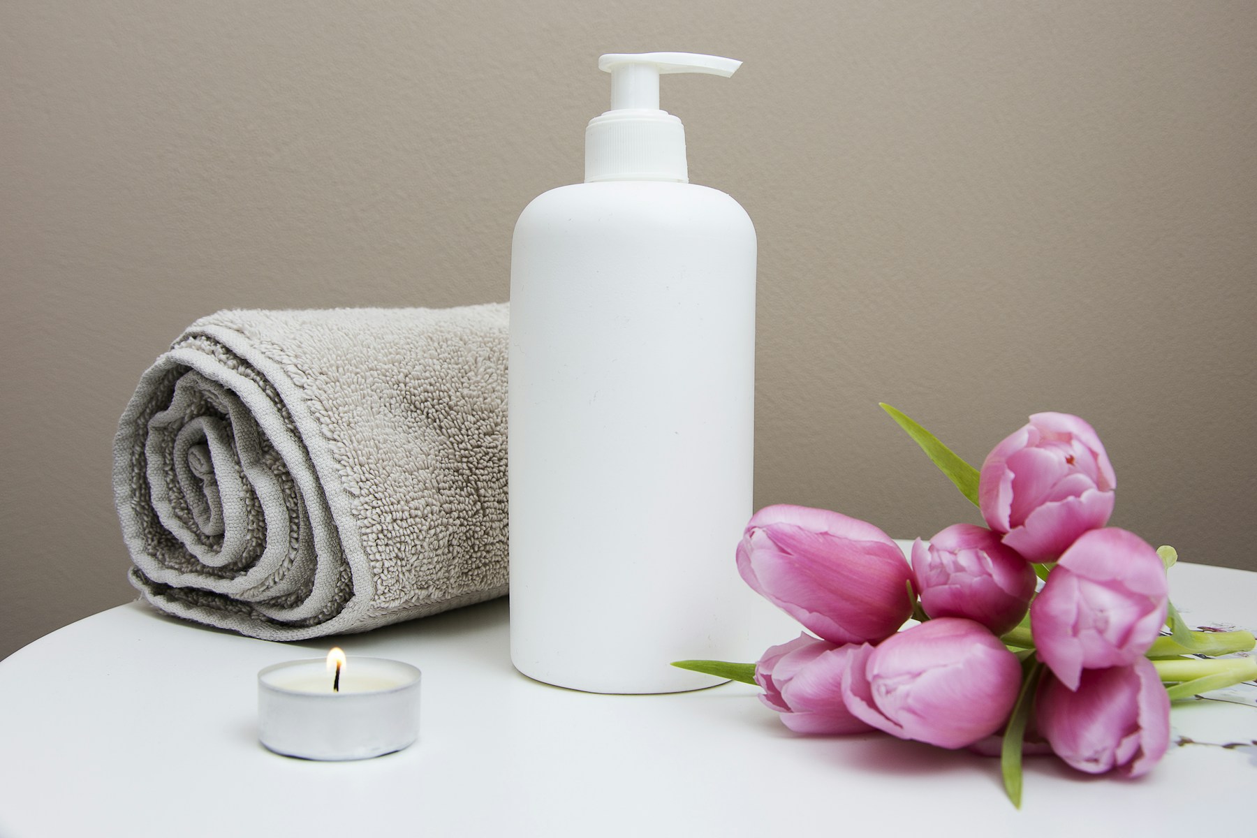 Unbranded pump bottle, towel, candle and tulips